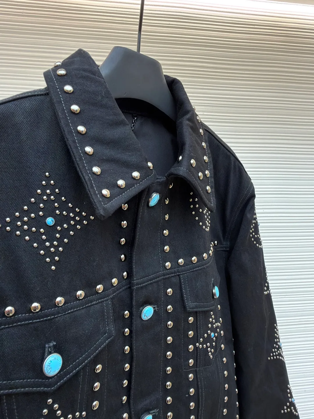 LOUIS VUITTON turquoise rivet denim jacket ●Original version: purchased and developed by 38979 ●Item number: 1682224-E30 ●Material: denim fabric ●Technology: hand-made rivet inlay ●Color: black ●Version: fitted version ●Weight: about 1550 grams ●Size: 46-48-50-52 ●Description: This black denim jacket is made of high-density twill denim fabric and has been treated with pre-washing water. It not only retains the crisp texture of the fabric, but also achieves a soft and skin-friendly wearing experience. The entire body of the garment is made of hand-made rivet inlay technology. The metal rivets are arranged at precise points to outline the outline of the brand's classic logo. Each rivet is manually hammered and fixed to ensure firmness and three-dimensionality. The placket and pockets are decorated with turquoise-textured resin buttons, which contrast with the metal rivets. The stitching on the collar, cuffs and hem adopts a double stitching process to enhance structural stability, while the edges are roughened to add a retro texture. The overall cut is a slightly loose Oversize version, combined with the three-dimensional tailoring process of the three-dimensional shoulder line, taking into account both styling and wearing comfort. Every detail is calibrated by hand, demonstrating the exquisite level of clothing making technology. The overall wiring is straight and delicate, the fabric is comfortable and soft, and the color is consistent without color difference. It can be matched with the same style to create a fashionable look and control various occasions. Customized accessories, complete with three standards, same style for men and women!
